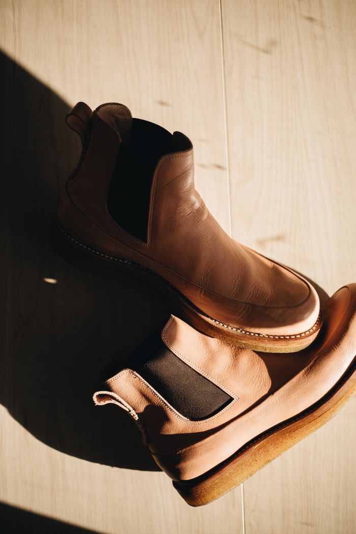 High-quality leather boots elegantly styled on a wooden floor with natural light.